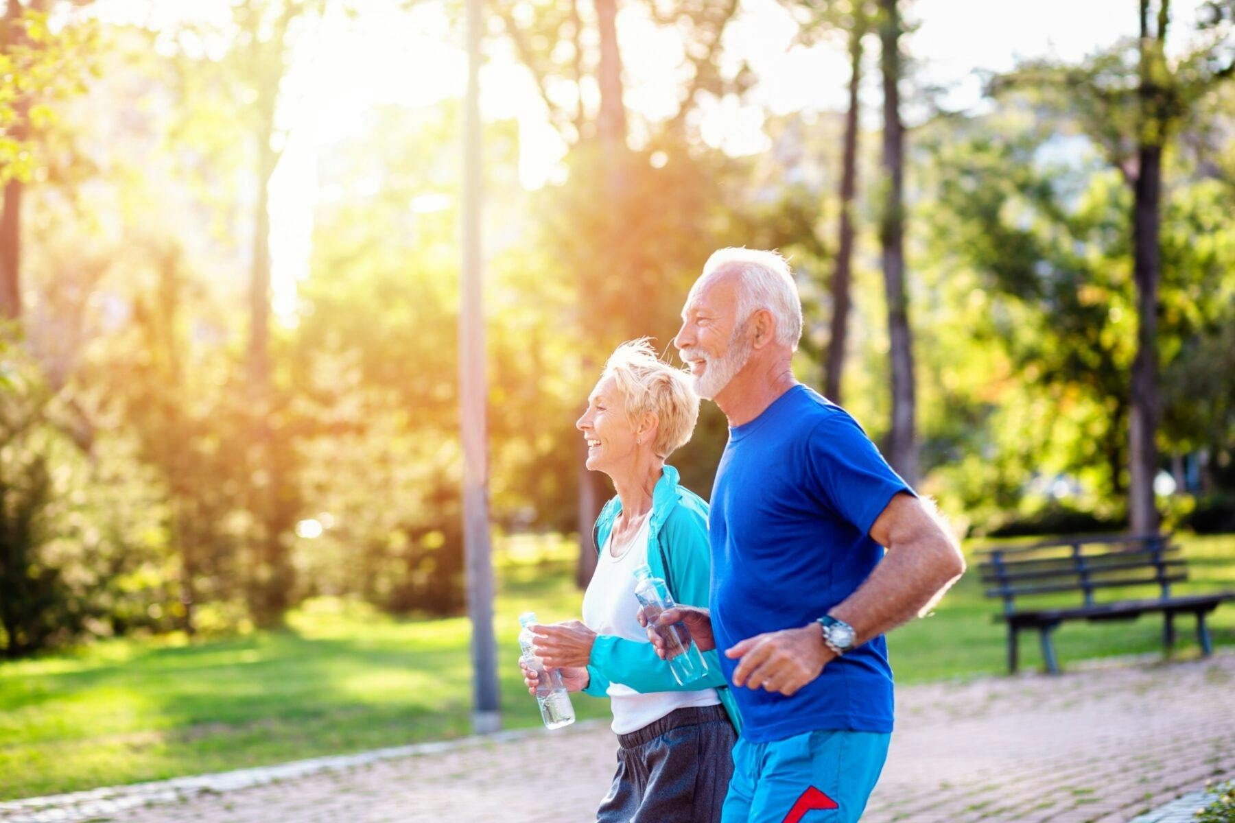 elderly couple running together outdoors in the park