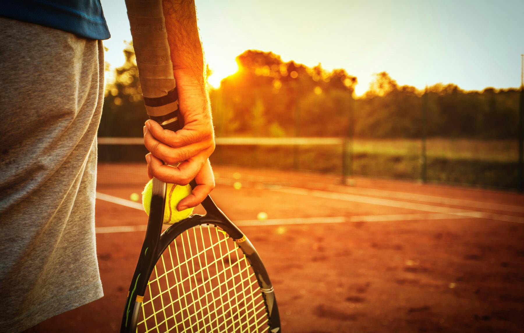 man holding a racket and looking at the sunset