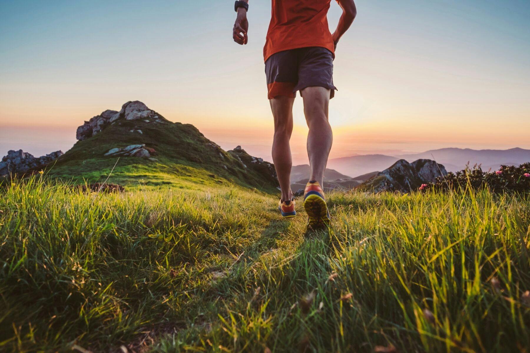 man trail running on a mountain at dusk