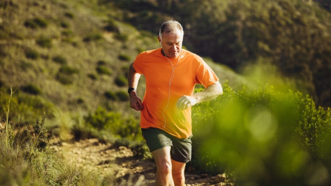 A man in his 60s goes for a run outside in the hills